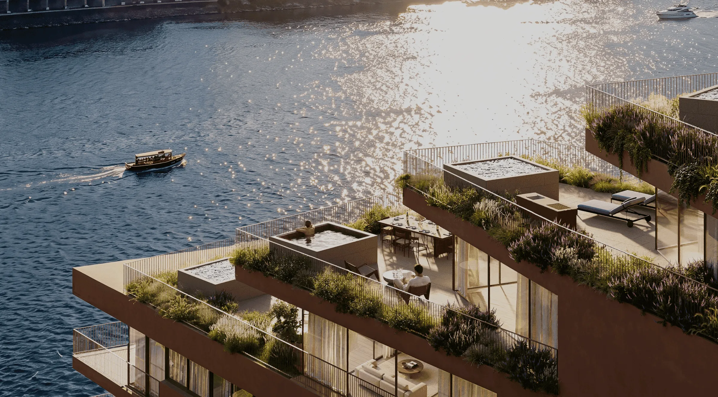 Luxury waterfront apartments featuring spacious rooftop terraces, private hot tubs, lush greenery, and outdoor seating areas, overlooking sparkling blue water with a small boat passing by in the golden sunlight.